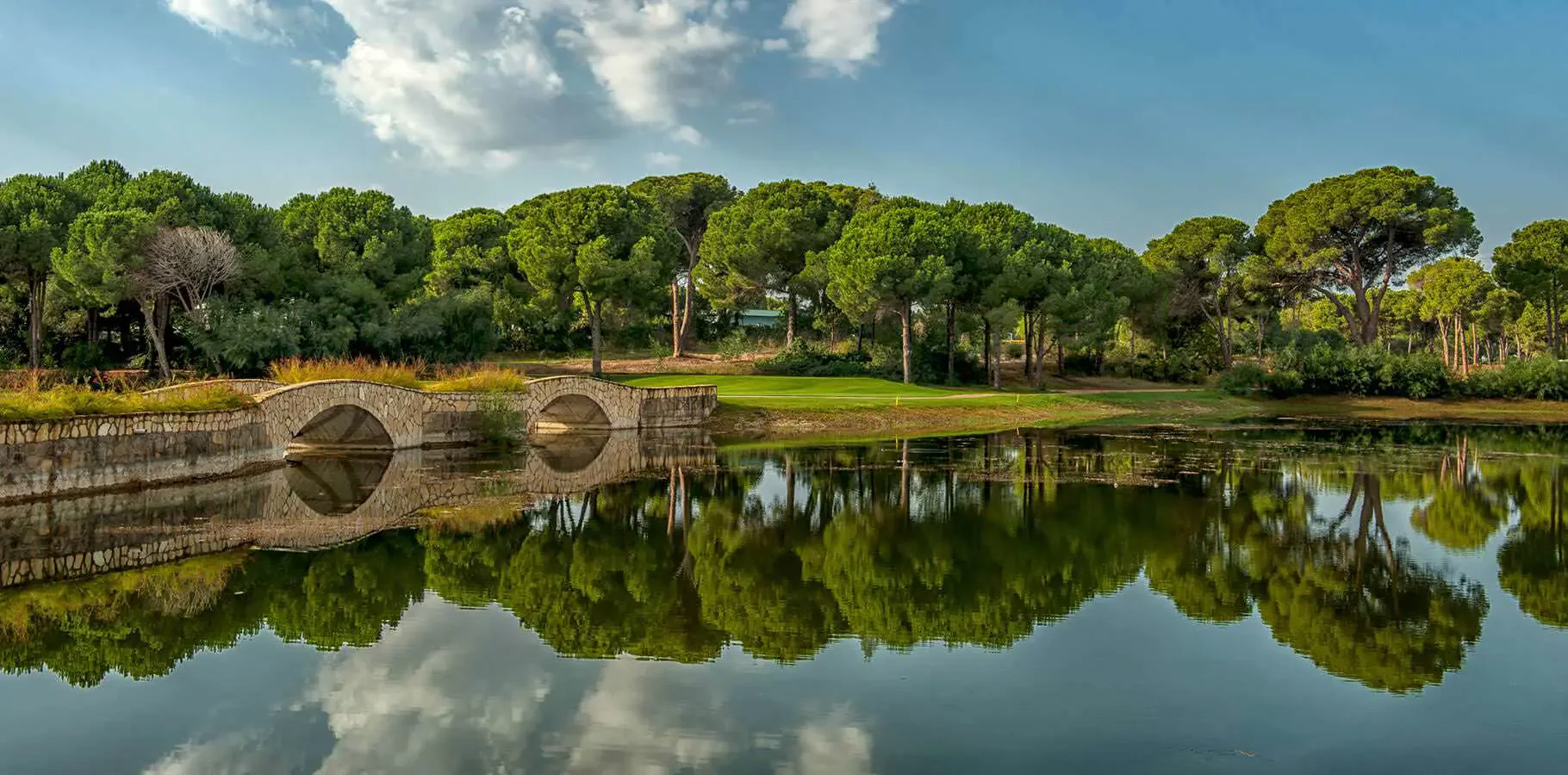 A stone bridge, lake and green on the nine-hole Gloria Verde Course