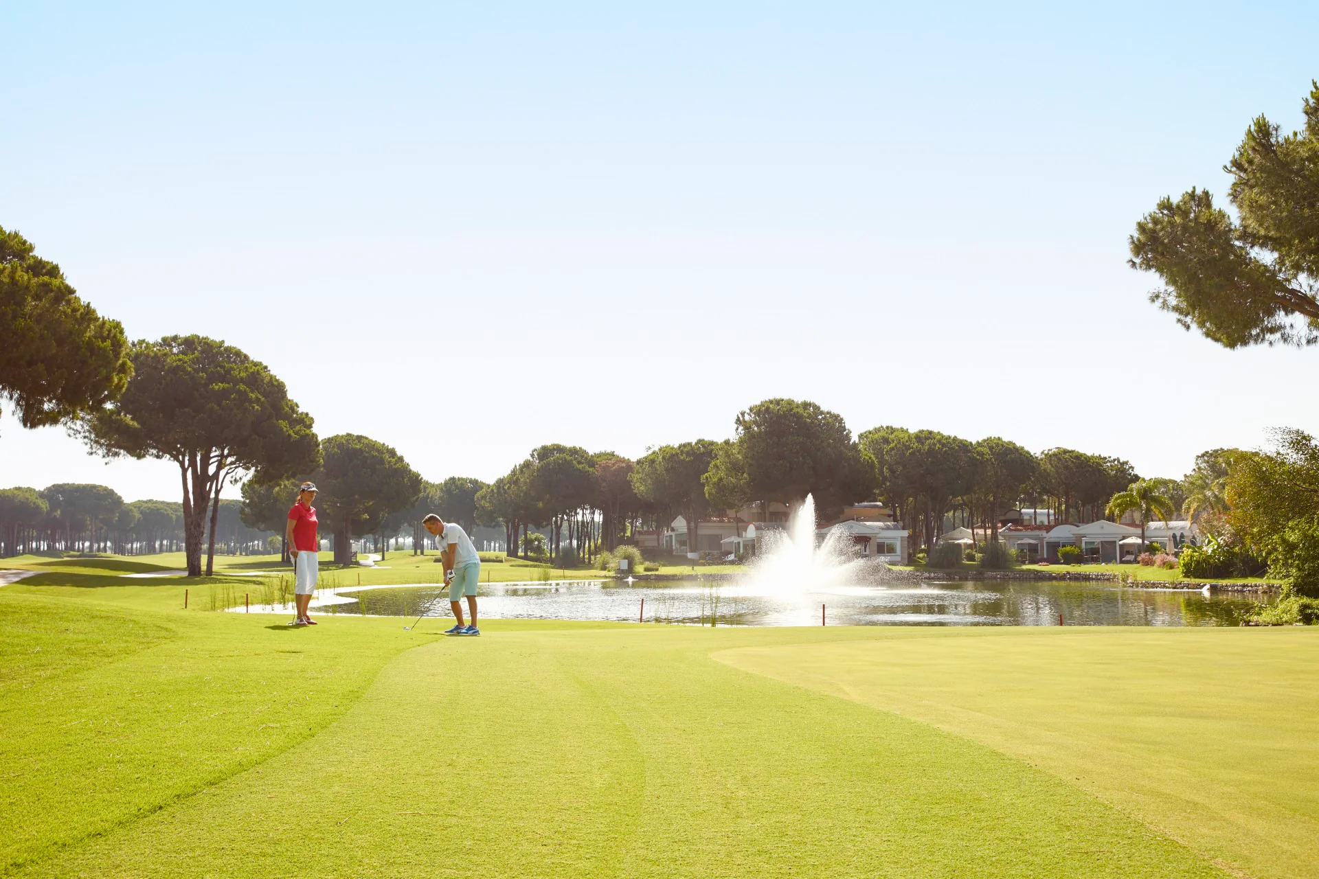 Golfers beside a lake-side green on ROBINSON Golf Club Nobilis